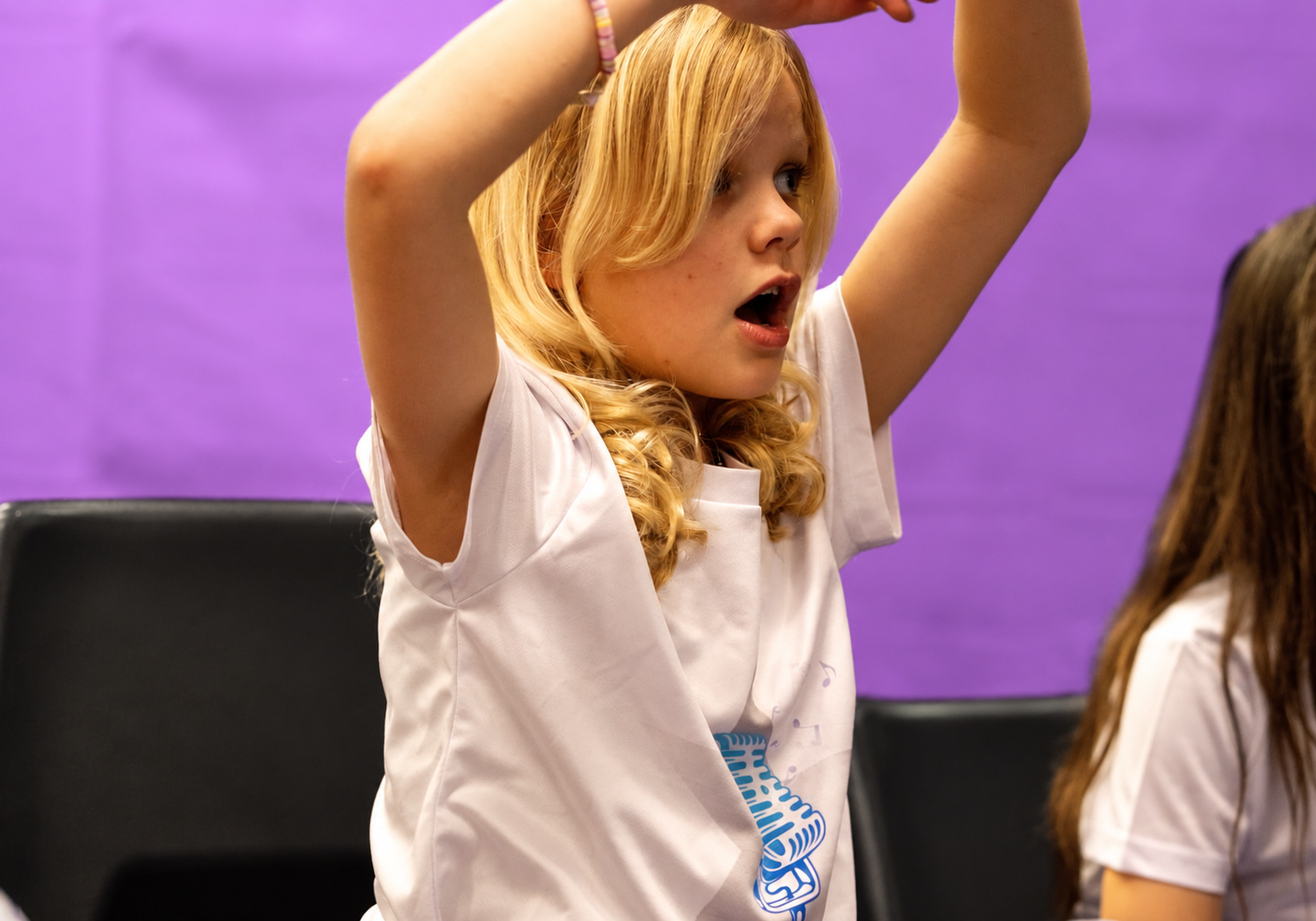 A Rising Stars singer raising her arms during a musical activity