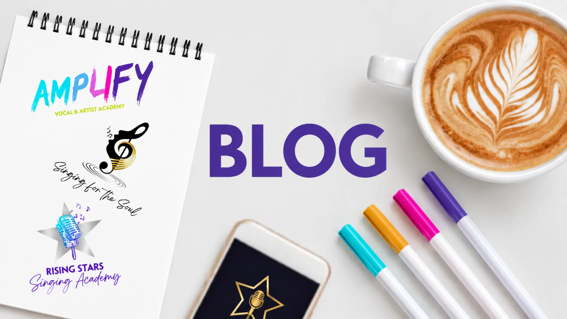 Blog banner with the Sing Dream Star programme logos — AMPLIFY, Singing for the Soul and Rising Stars — on a notepad beside a coffee, phone and pen on a wooden desk