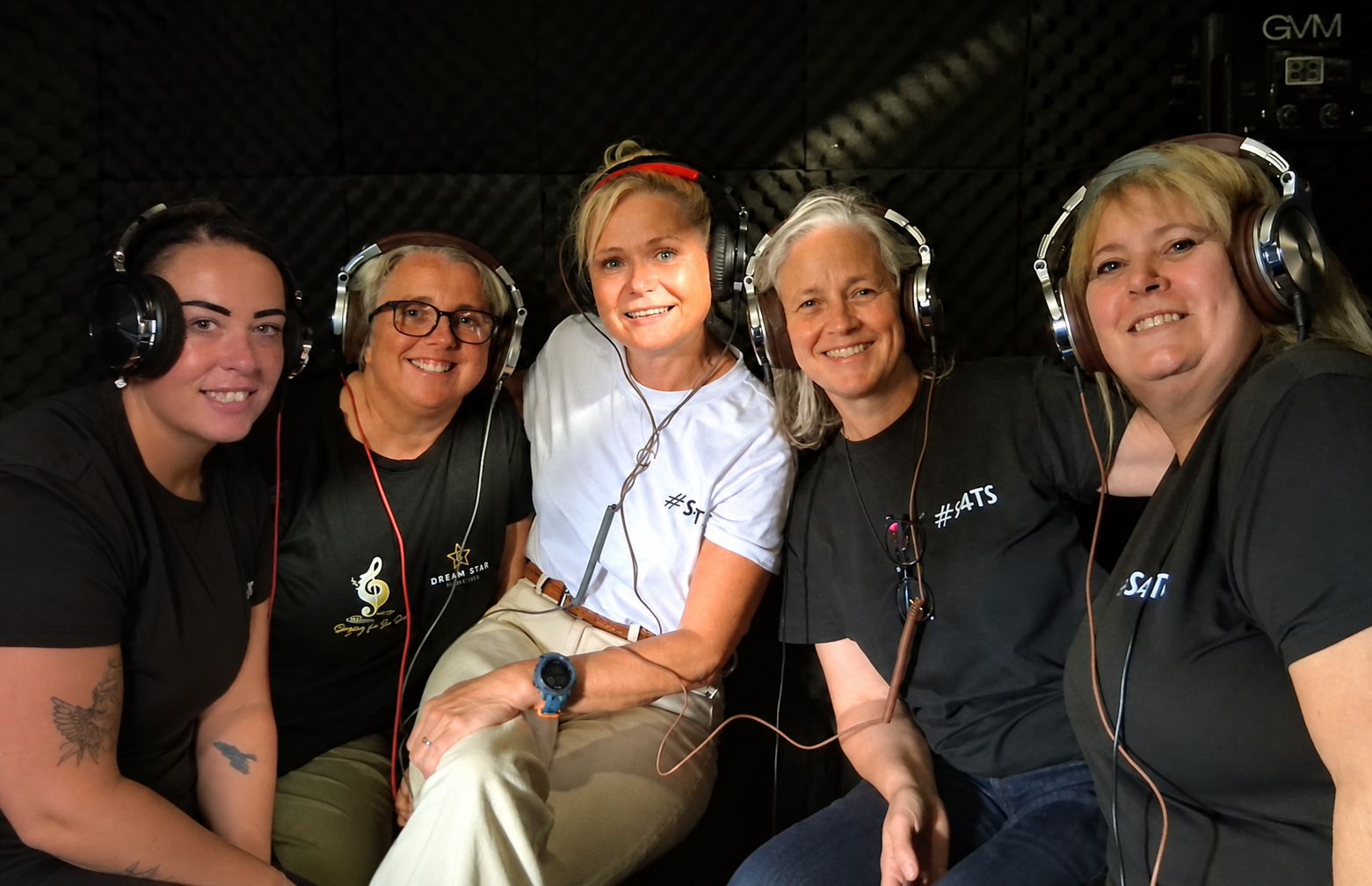 Five Singing for the Soul friends wearing headphones together in the recording studio