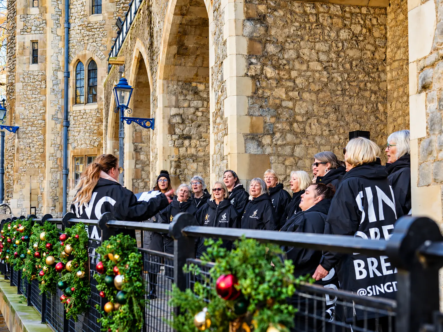 Choir members singing beside historic stone arches