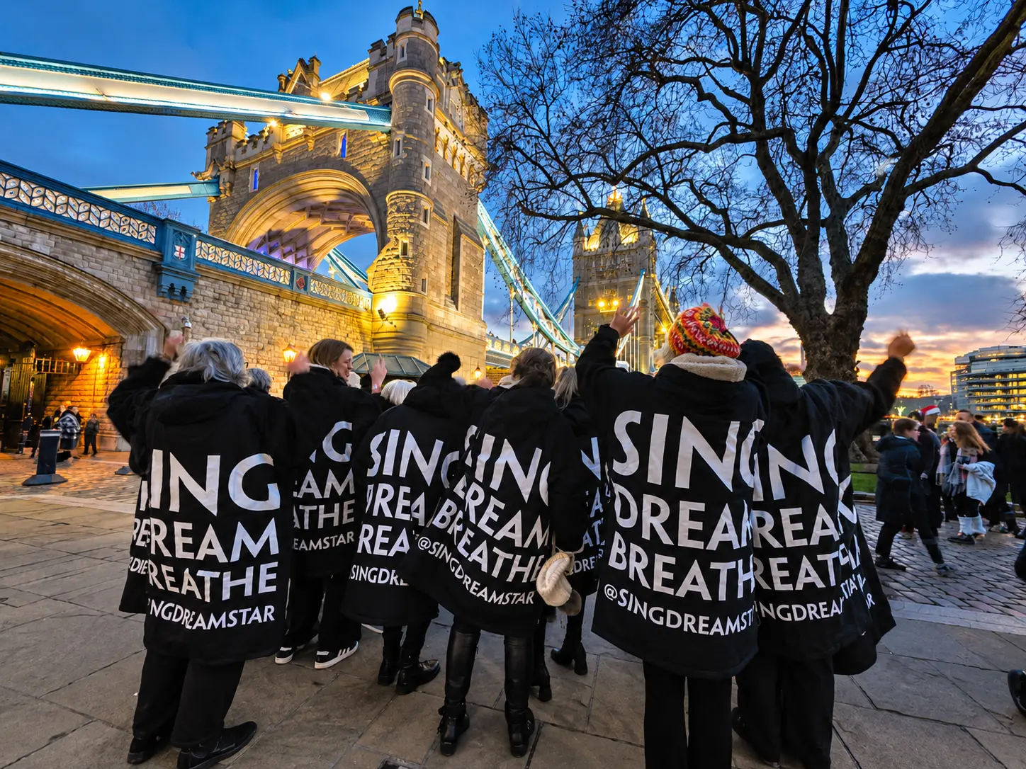 Choir members together beside Tower Bridge in the evening