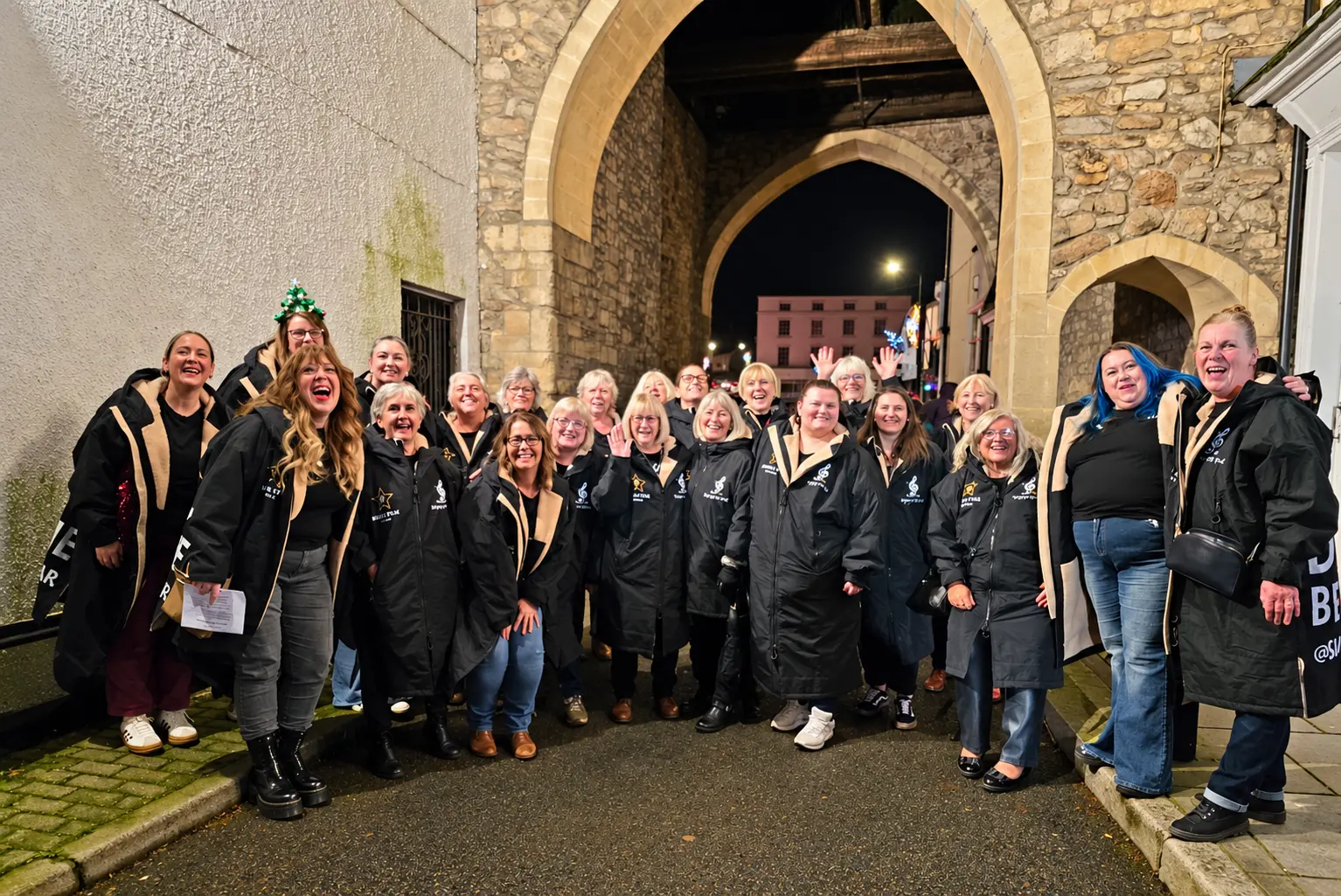 Choir members gathered beneath Chepstow’s stone archway at night