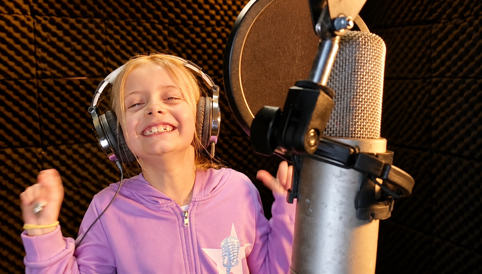 A young Rising Stars singer laughing at the studio microphone