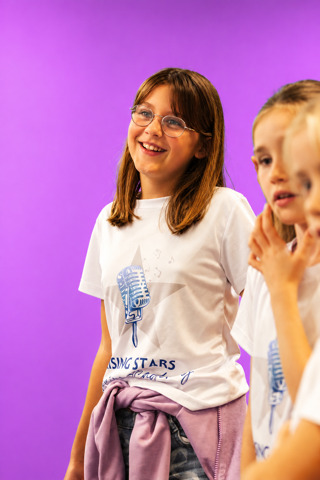 A Rising Stars singer smiling in her white Rising Stars t-shirt